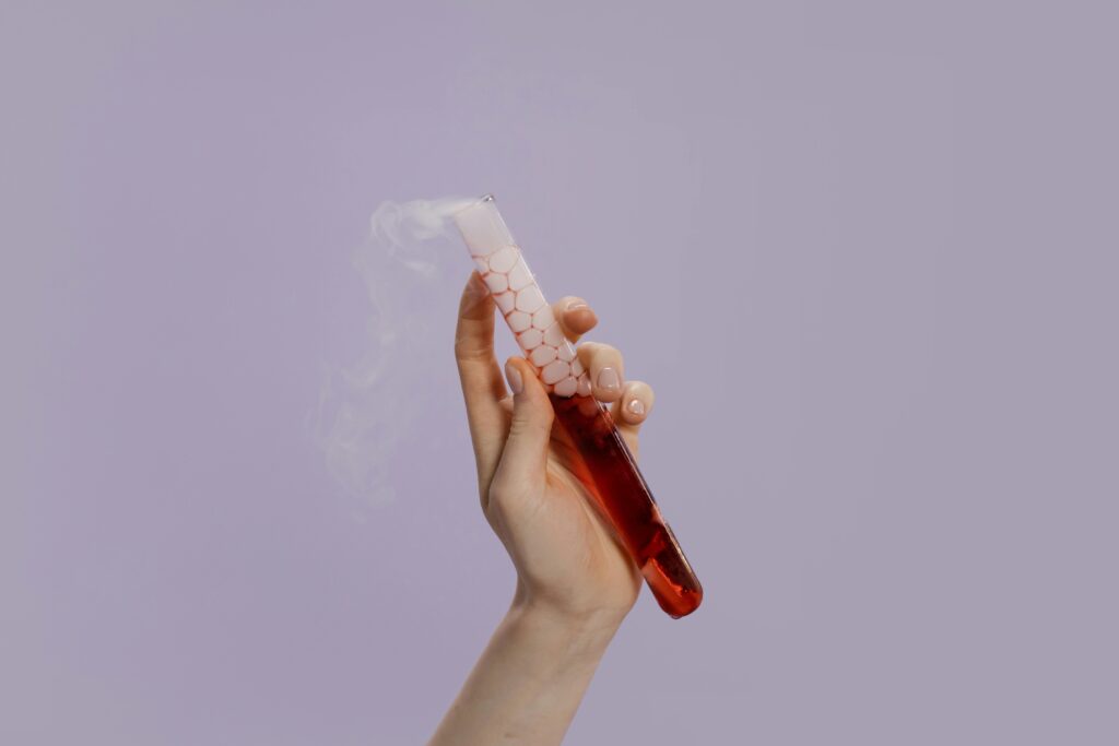 A hand holds a smoking test tube with vibrant red liquid and vapor, symbolizing scientific experimentation.