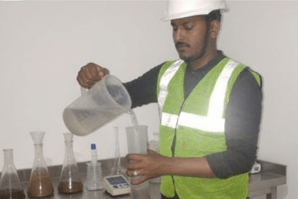 A laboratory analyst collecting samples of soil and sludge to analyze for contaminants.